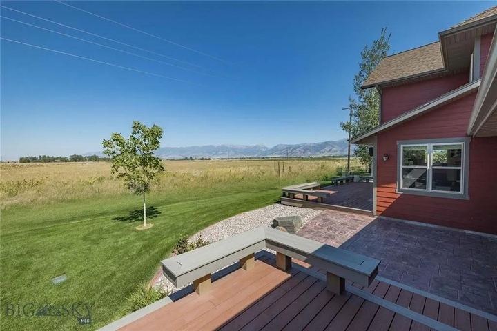 Back deck and patio with built-in benches beside the house, overlooking a field toward the mountains