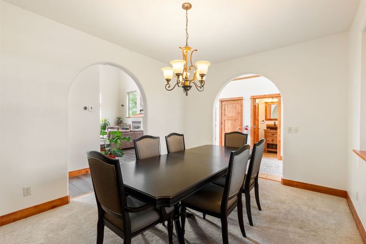 Formal dining room with a dark wood table for six, a chandelier, and arched doorways