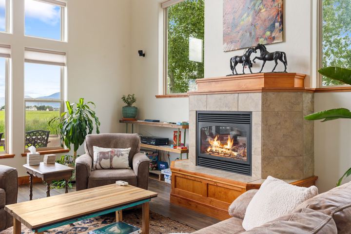 Living room seating around a tiled fireplace with tall windows on both sides