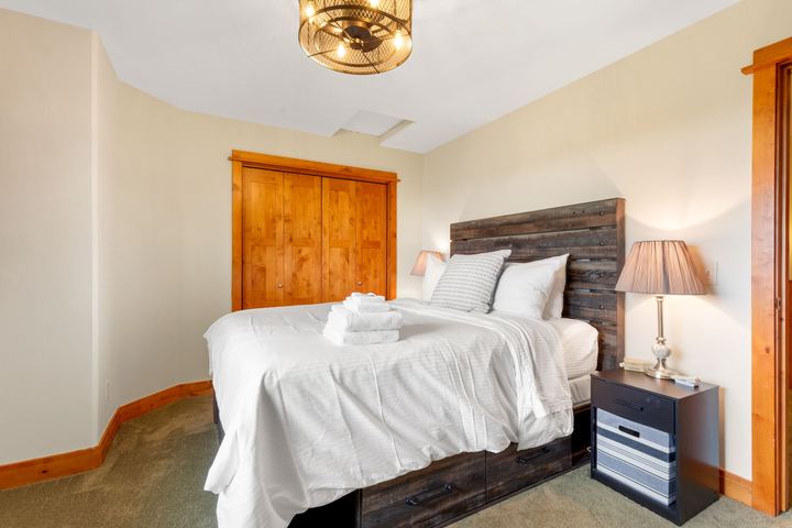 Upstairs bedroom with a wood headboard, white bedding, a bedside lamp, and a closet